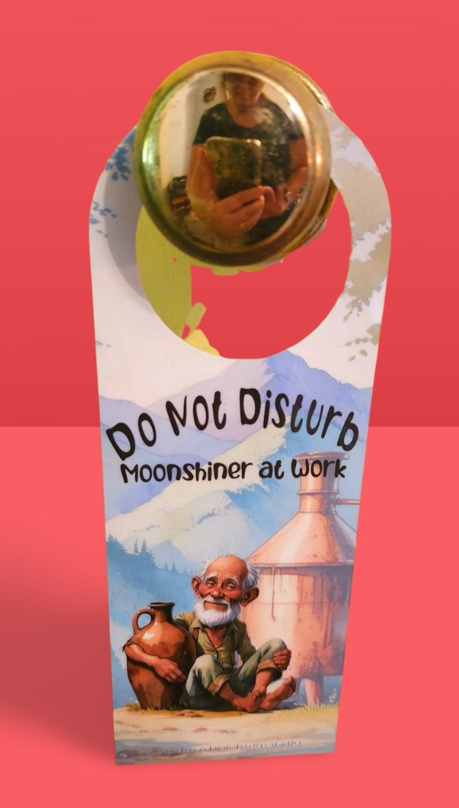 Door hanger with illustration of a moonshiner and text 'Do Not Disturb Moonshiner at Work' on a red background
