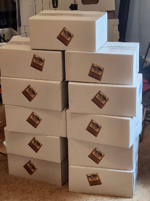 Stack of white boxes with a logo on a textured surface