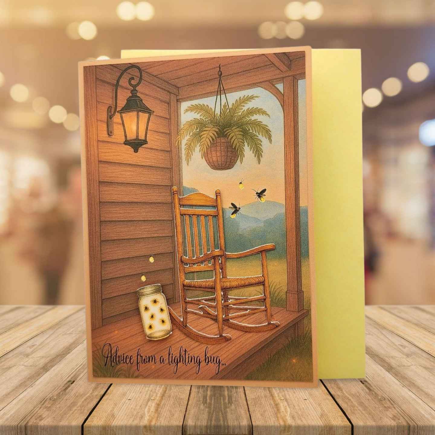 Greeting card with a rocking chair on a porch scene, placed on a wooden surface.