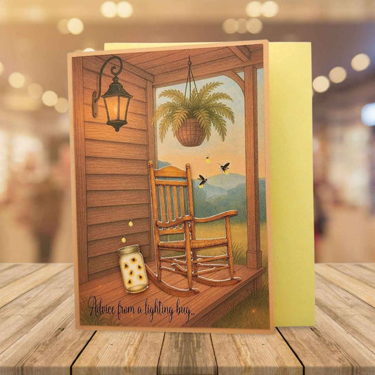 Greeting card with a rocking chair on a porch scene, placed on a wooden surface.