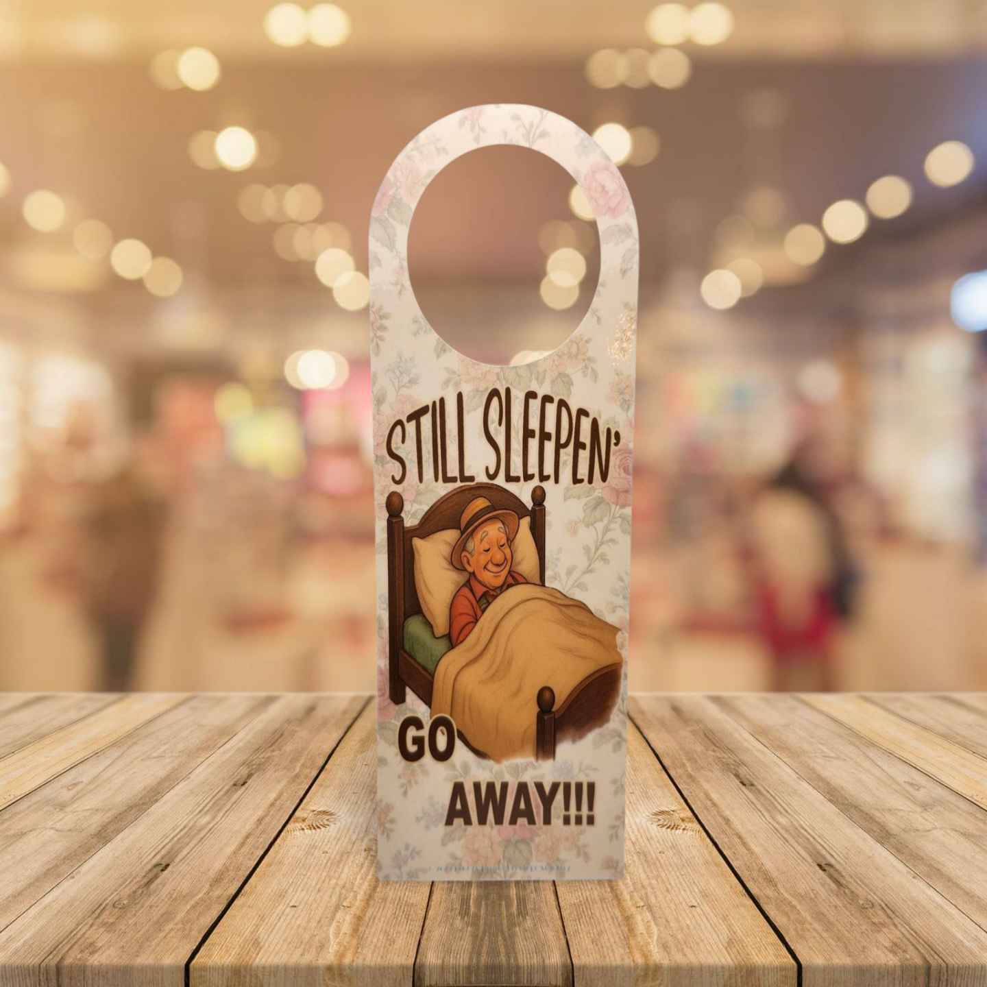 Door hanger with cartoon character and text 'STILL SLEEPEN GO AWAY!!!' on a wooden surface.