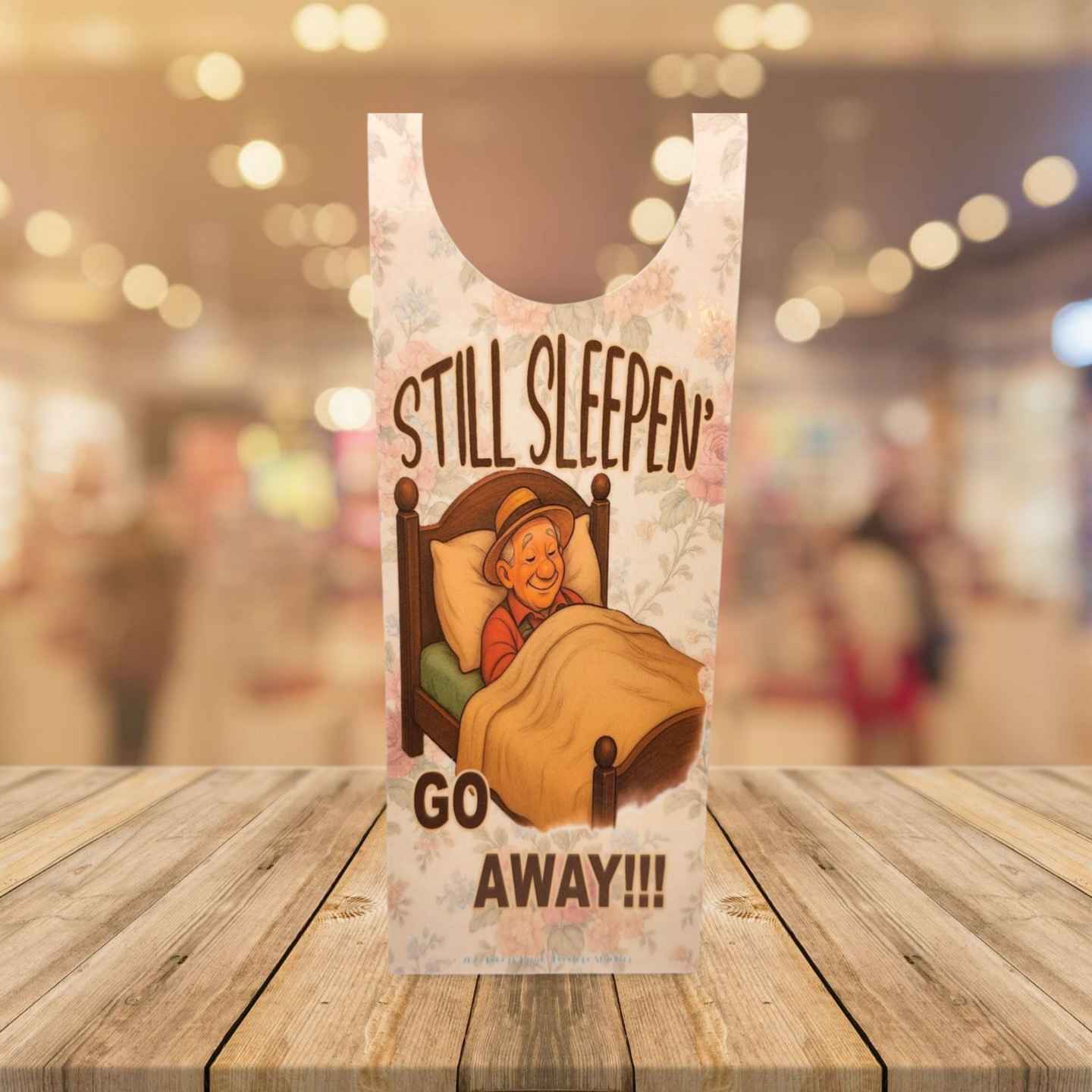 Plastic bag with cartoon character and text 'STILL SLEEPEN GO AWAY!!!' on a wooden surface.