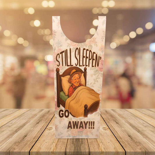 Plastic bag with cartoon character and text 'STILL SLEEPEN GO AWAY!!!' on a wooden surface.
