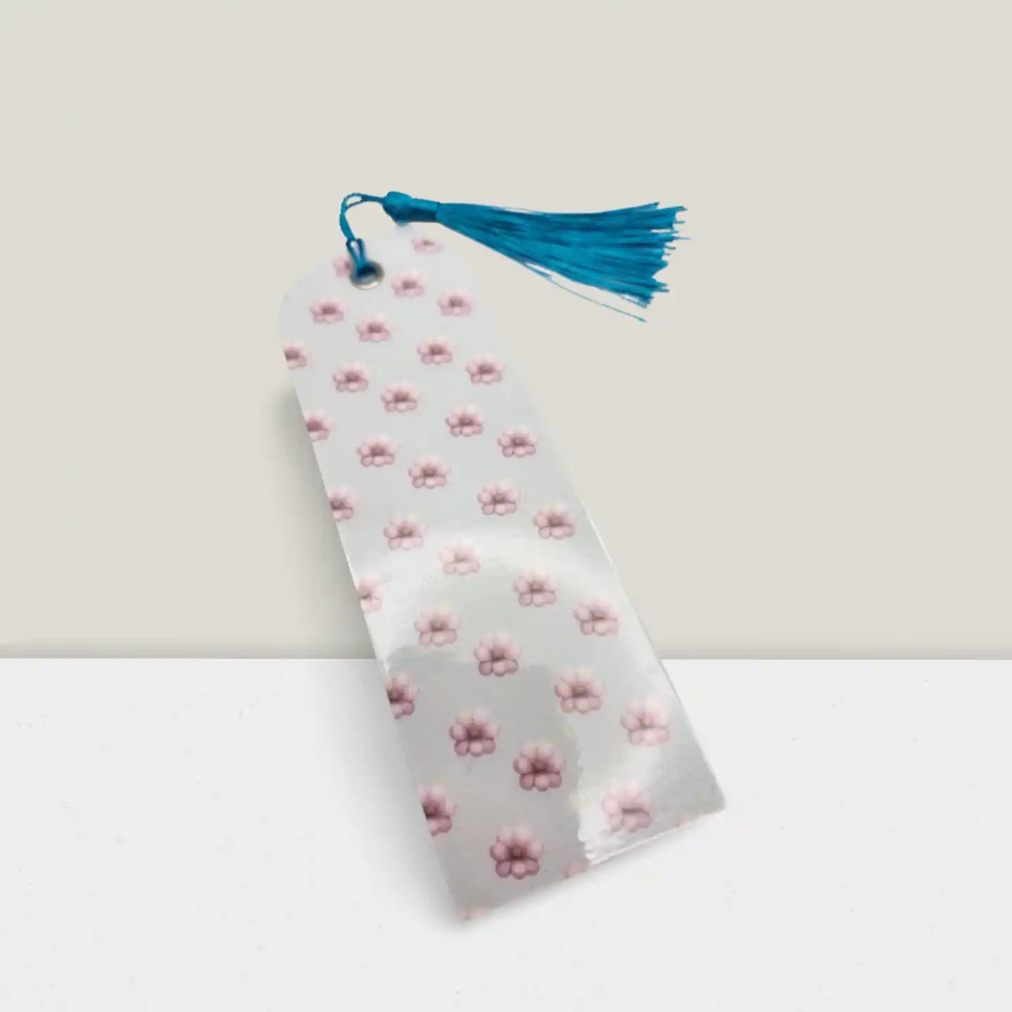 Floral-patterned bookmark with a blue tassel on a light gray background