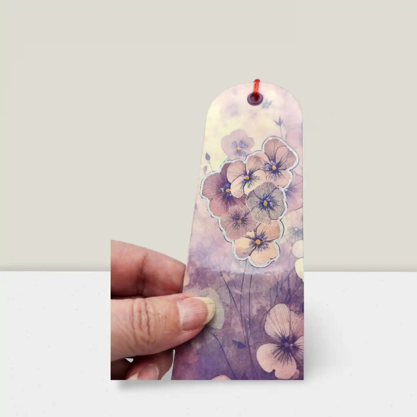 Floral bookmark held by a hand against a plain background