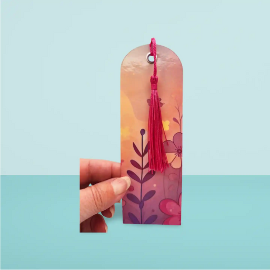 Decorative bookmark with a pink tassel held by a hand on a light blue background