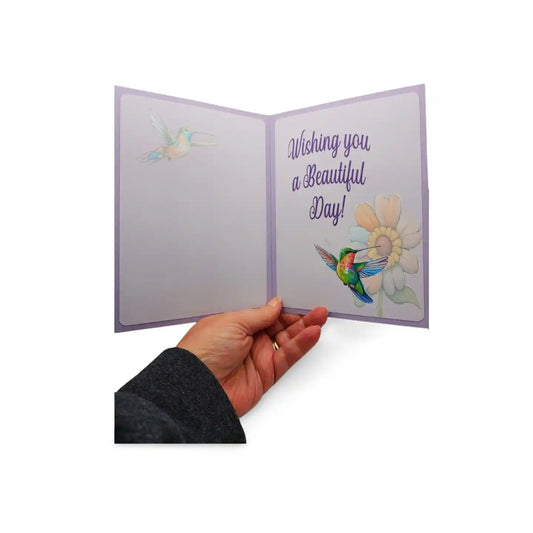 Hand holding a card with colorful hummingbird illustrations and text on a white background