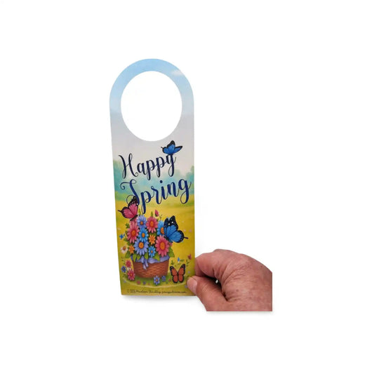 Hand holding a 'Happy Spring' door hanger with butterflies and flowers on a white background