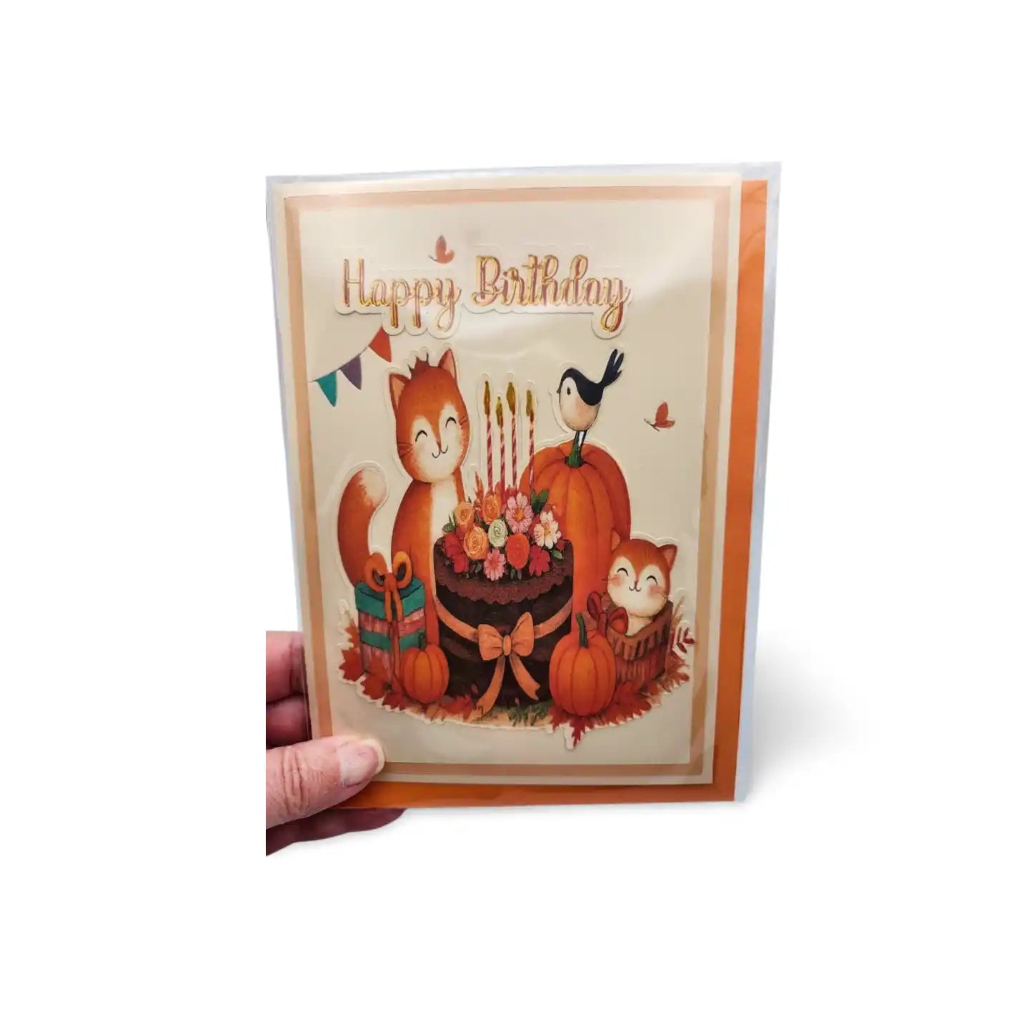 Birthday card with foxes, pumpkins, and candles held by a hand on a white background