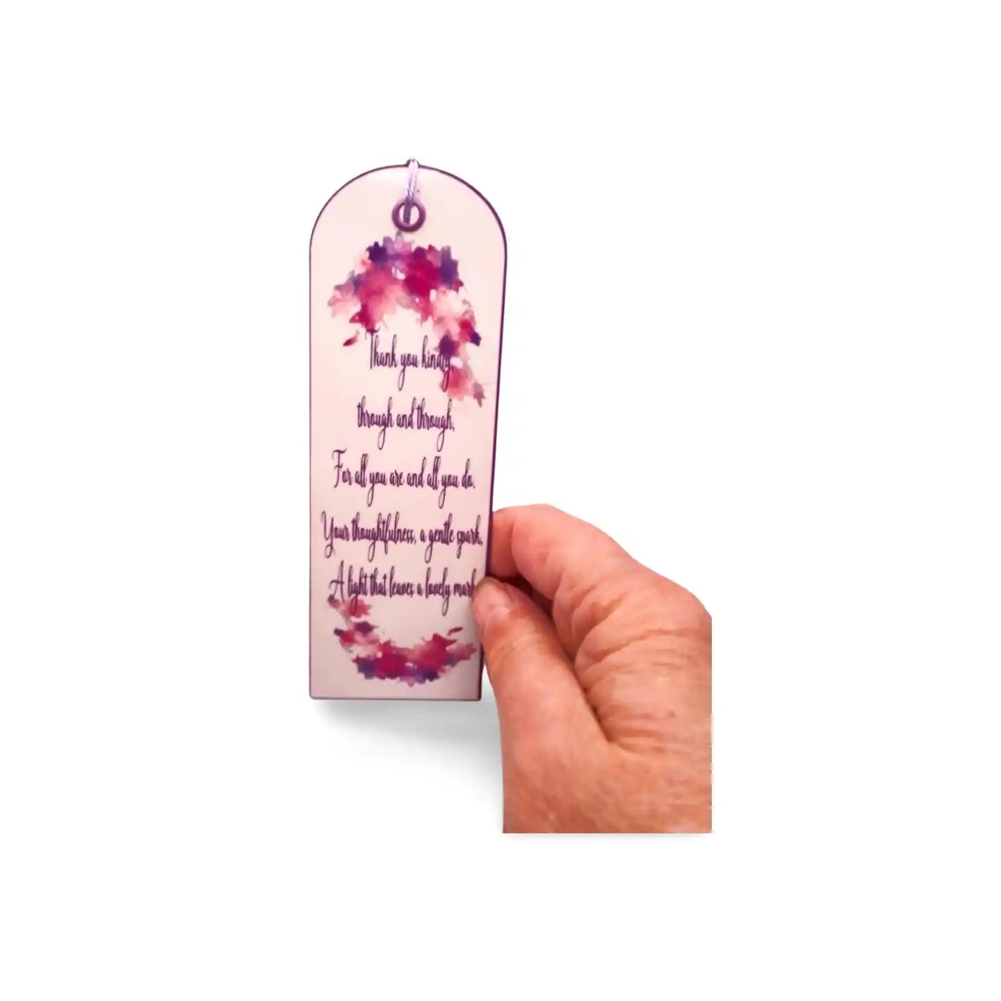 Hand holding a bookmark with floral design and text on a white background