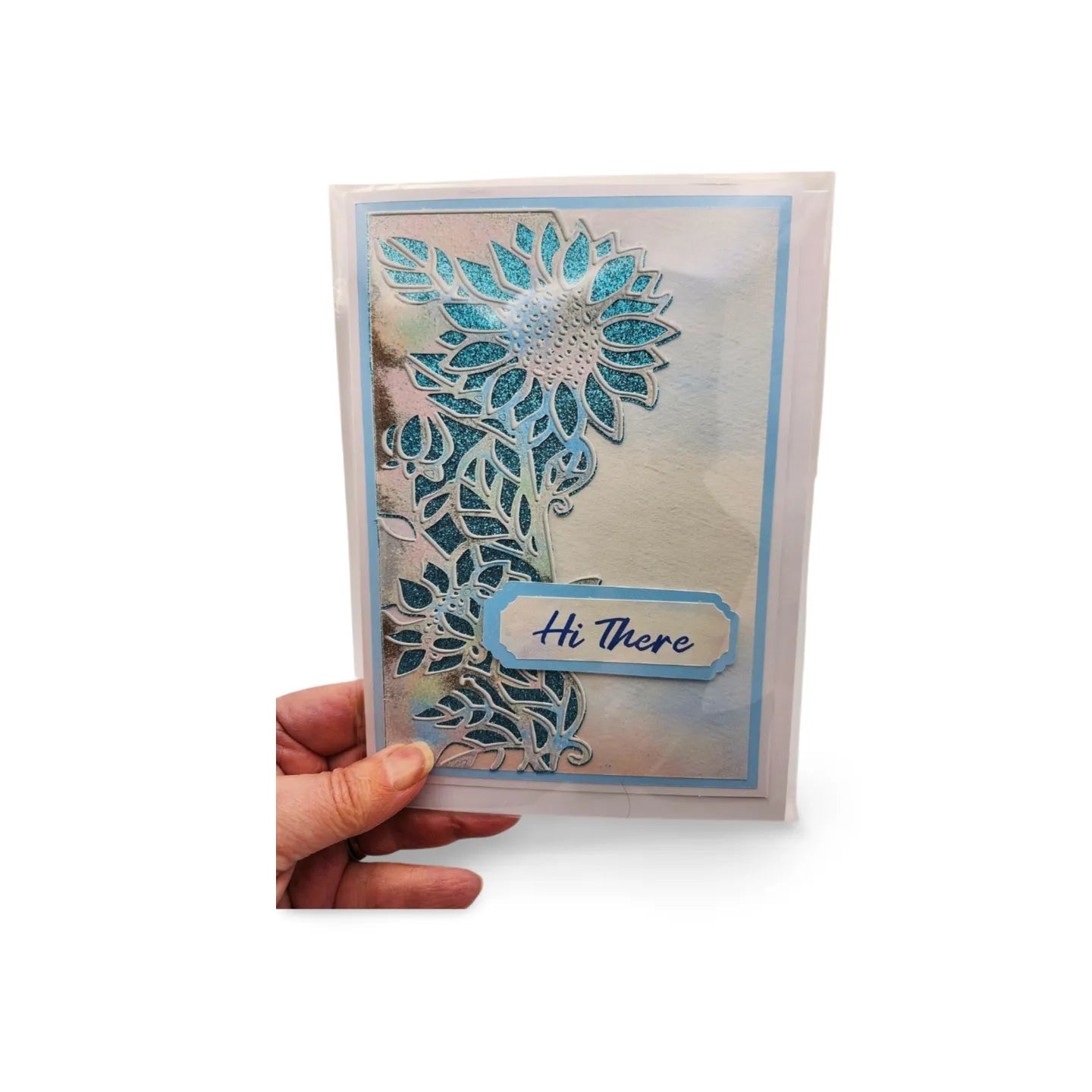 Hand holding a card with a decorative floral design and 'Hi There' text on a white background
