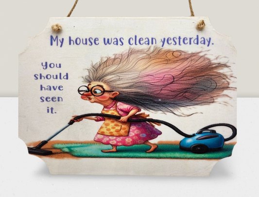 Decorative sign with cartoon character using a vacuum cleaner and humorous text.