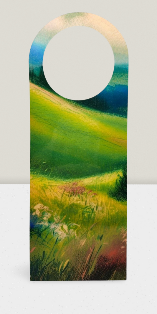 Decorative door hanger with a painted landscape of a field and sky.