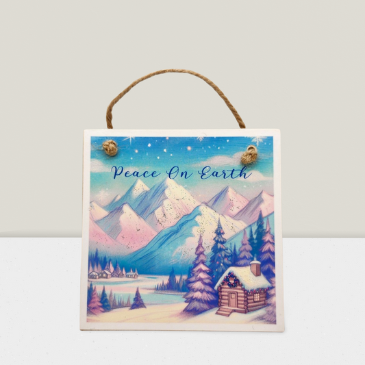 Decorative sign with a winter landscape and 'Peace On Earth' text on a white background