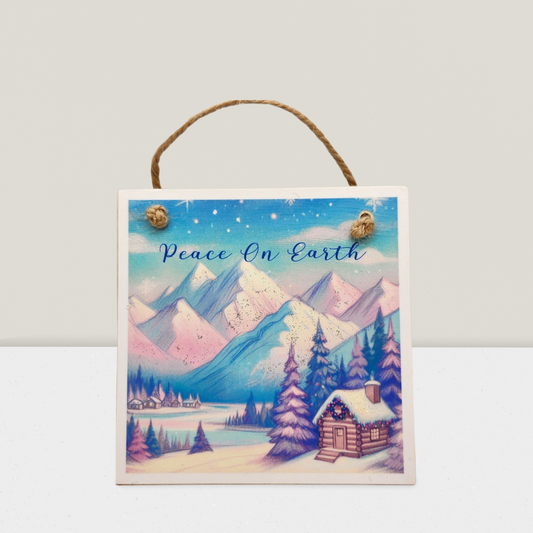 Decorative sign with a winter landscape and 'Peace On Earth' text on a plain background