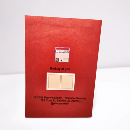 Red greeting card with text and a small window showing a photo on a white background