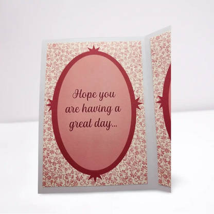 Greeting card with pink balloon design and text 'Hope you are having a great day...' on a floral patterned background.