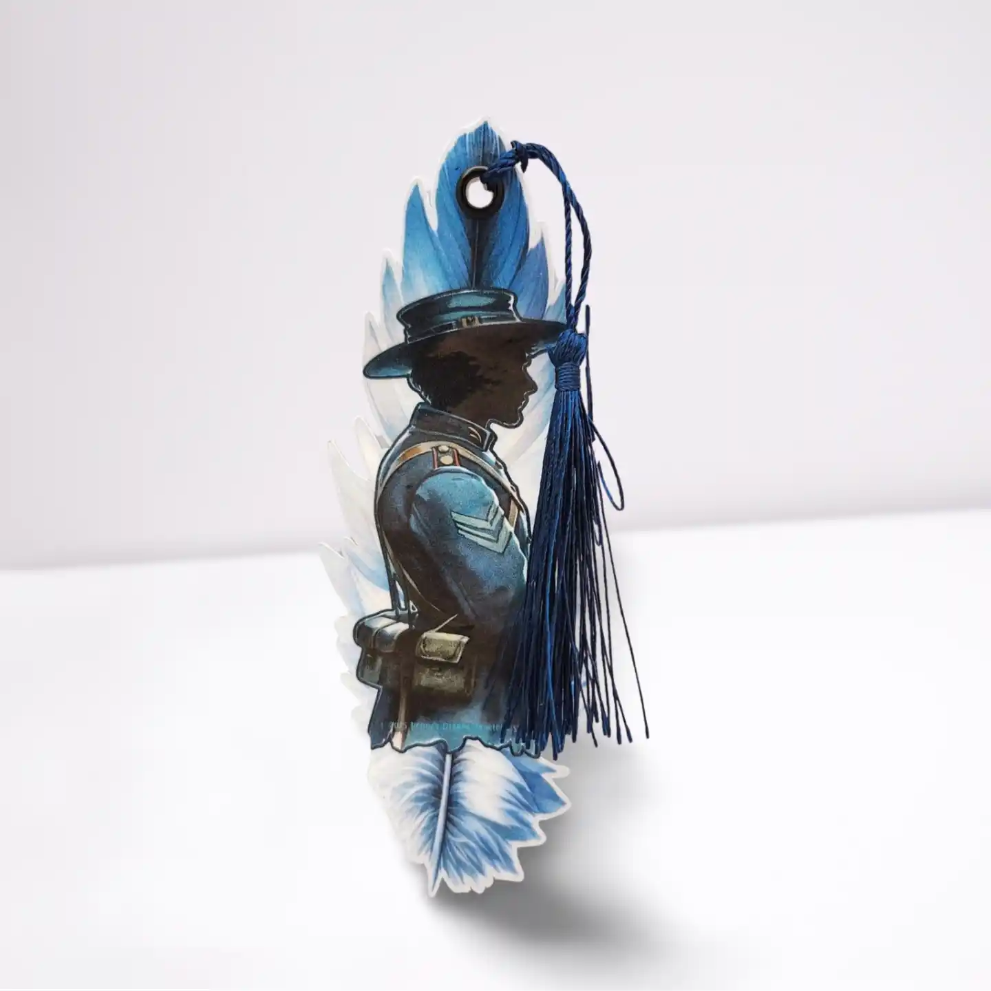 Decorative item with a silhouette of a person wearing a hat and a blue feather, on a white background.