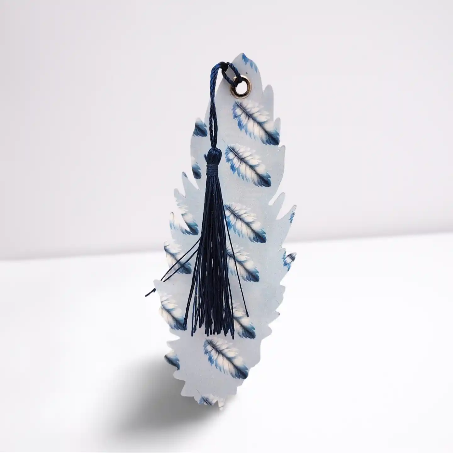 Decorative feather-shaped object with a tassel on a white background