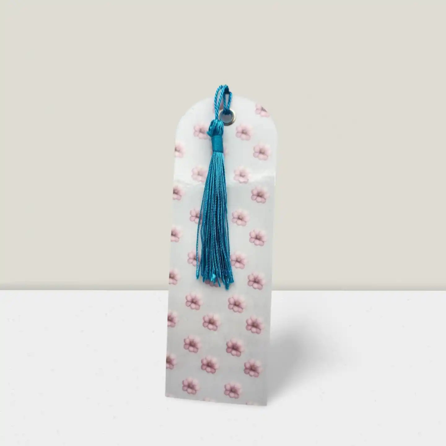 Decorative bookmark with floral pattern and blue tassel on a light gray background