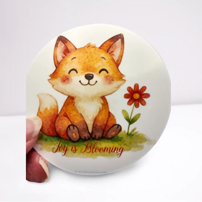 Round sticker with a fox illustration and 'Joy is Blooming' text on a white background