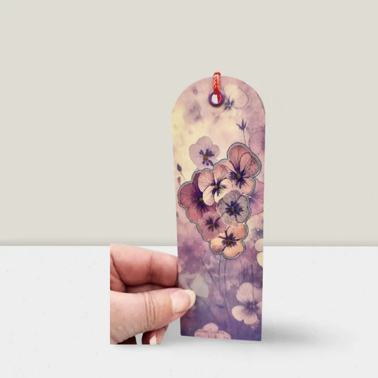 Floral bookmark held by a hand on a white background