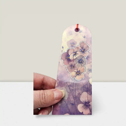 Floral bookmark held by a hand against a plain background