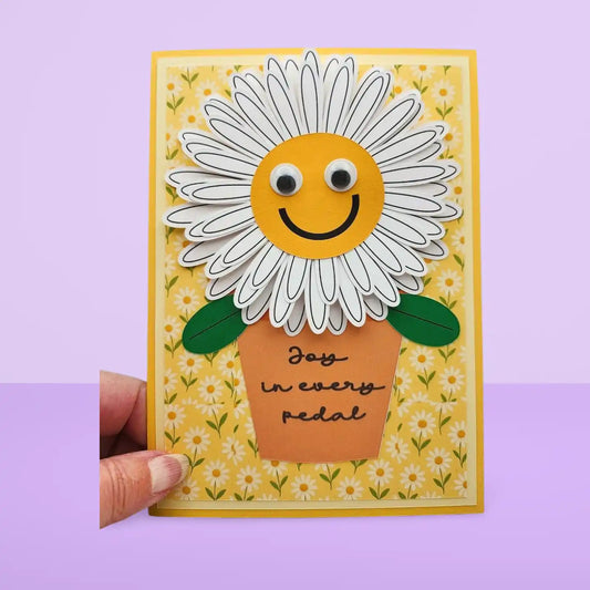 Card with a smiling sunflower design and 'Joy in every pedal' text on a yellow background.