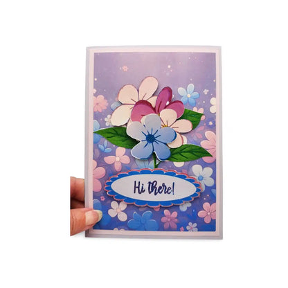Colorful floral greeting card with 'Hi There!' text held by a hand on a white background