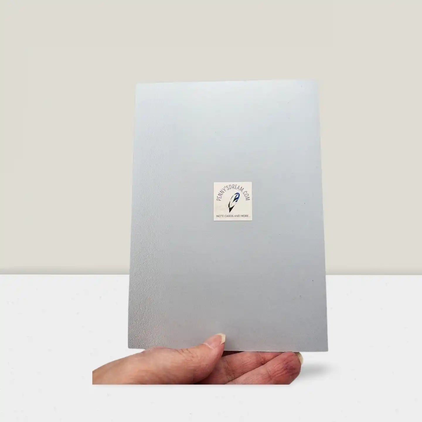 Hand holding a light gray card with a logo on a white background