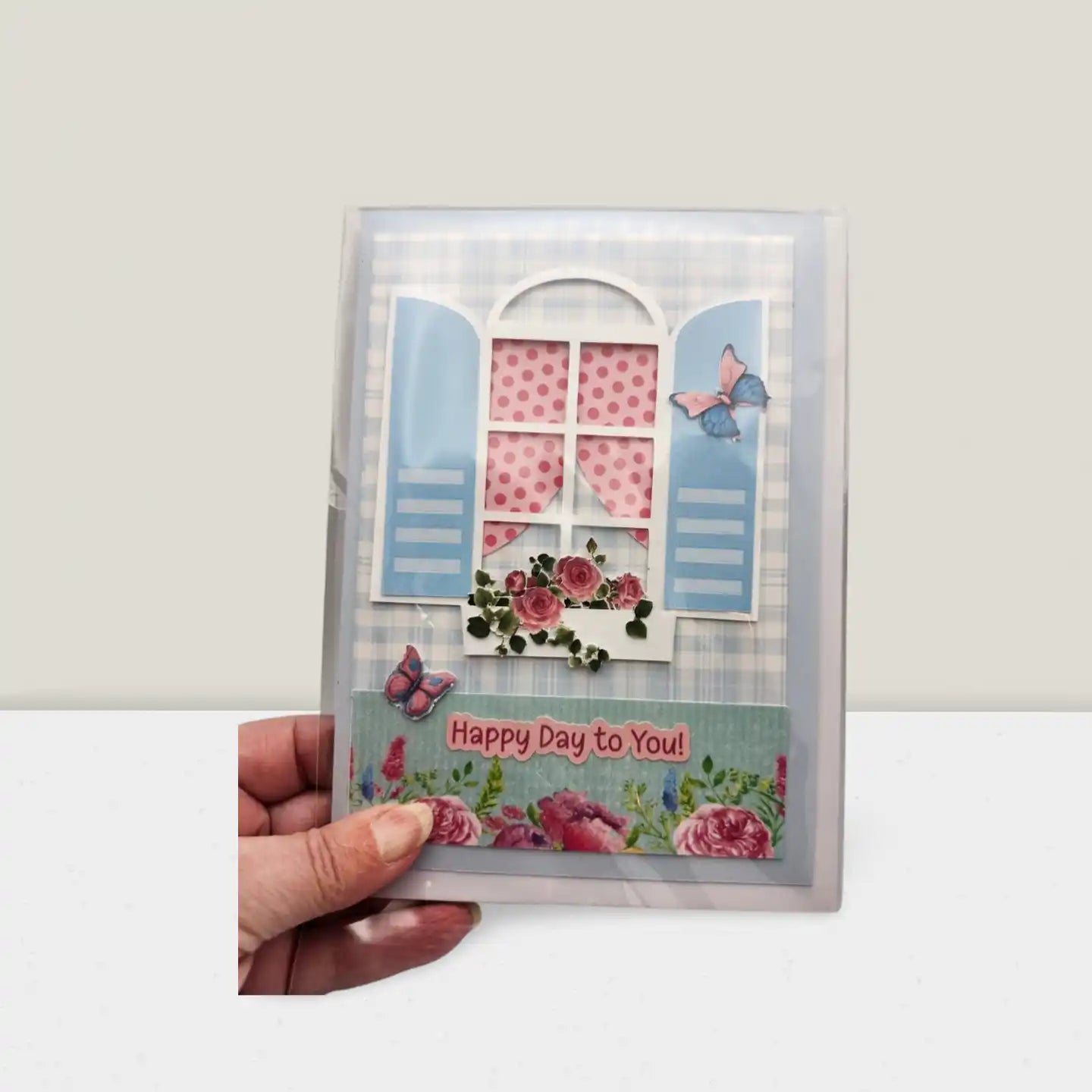 Greeting card with floral design and 'Happy Day to You!' text held by a hand against a white background