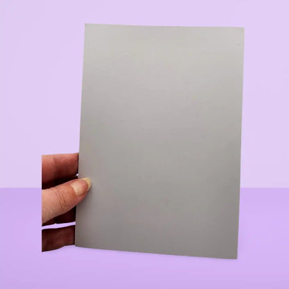 Hand holding a gray card against a purple background