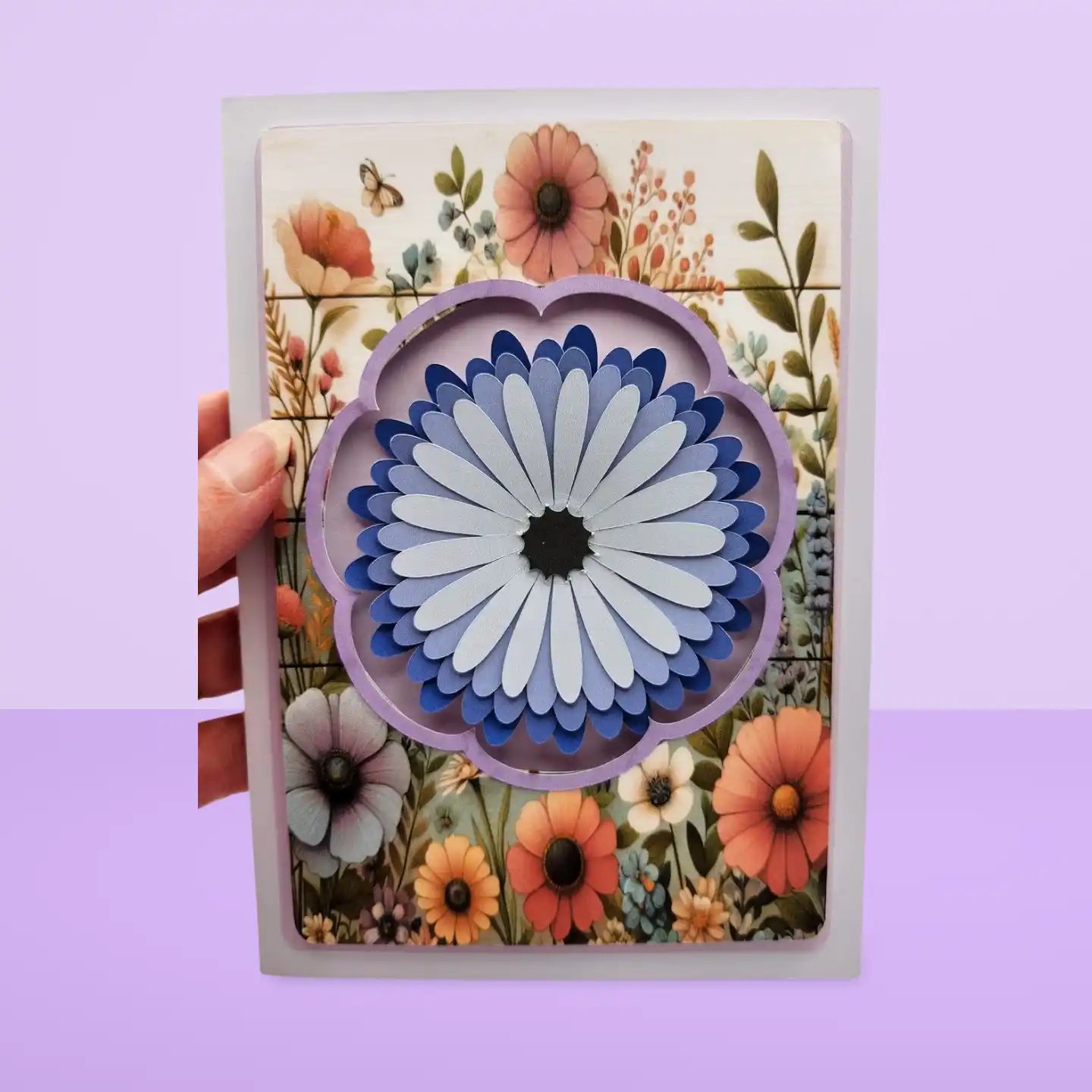 Card with a floral design and a decorative flower cutout on a purple background