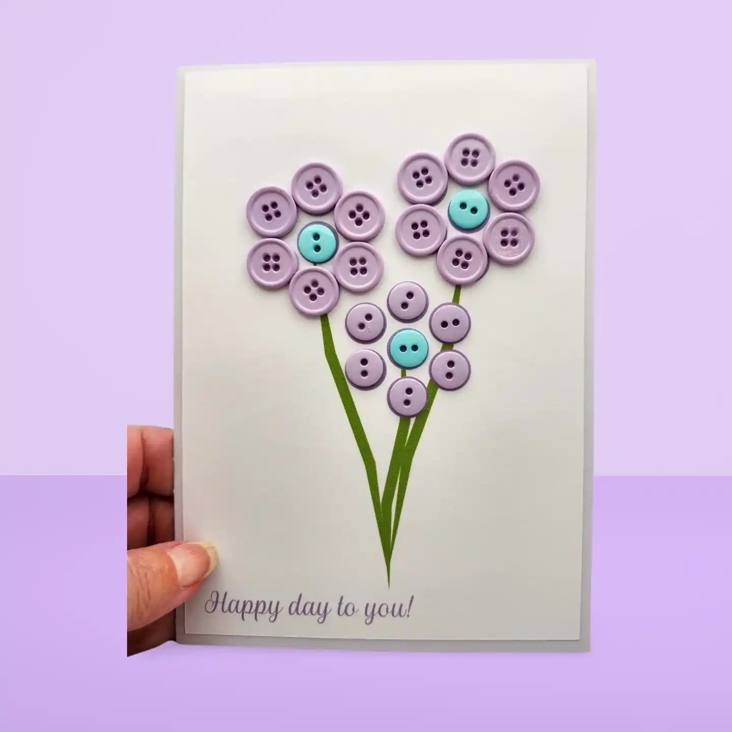 Card with button flowers and 'Happy day to you!' text on a purple background