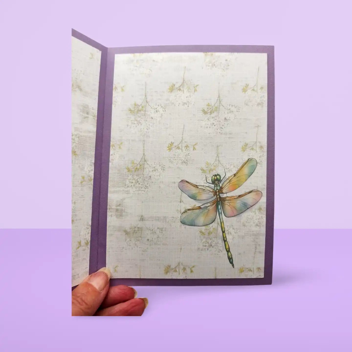 Card with a dragonfly design held against a purple background
