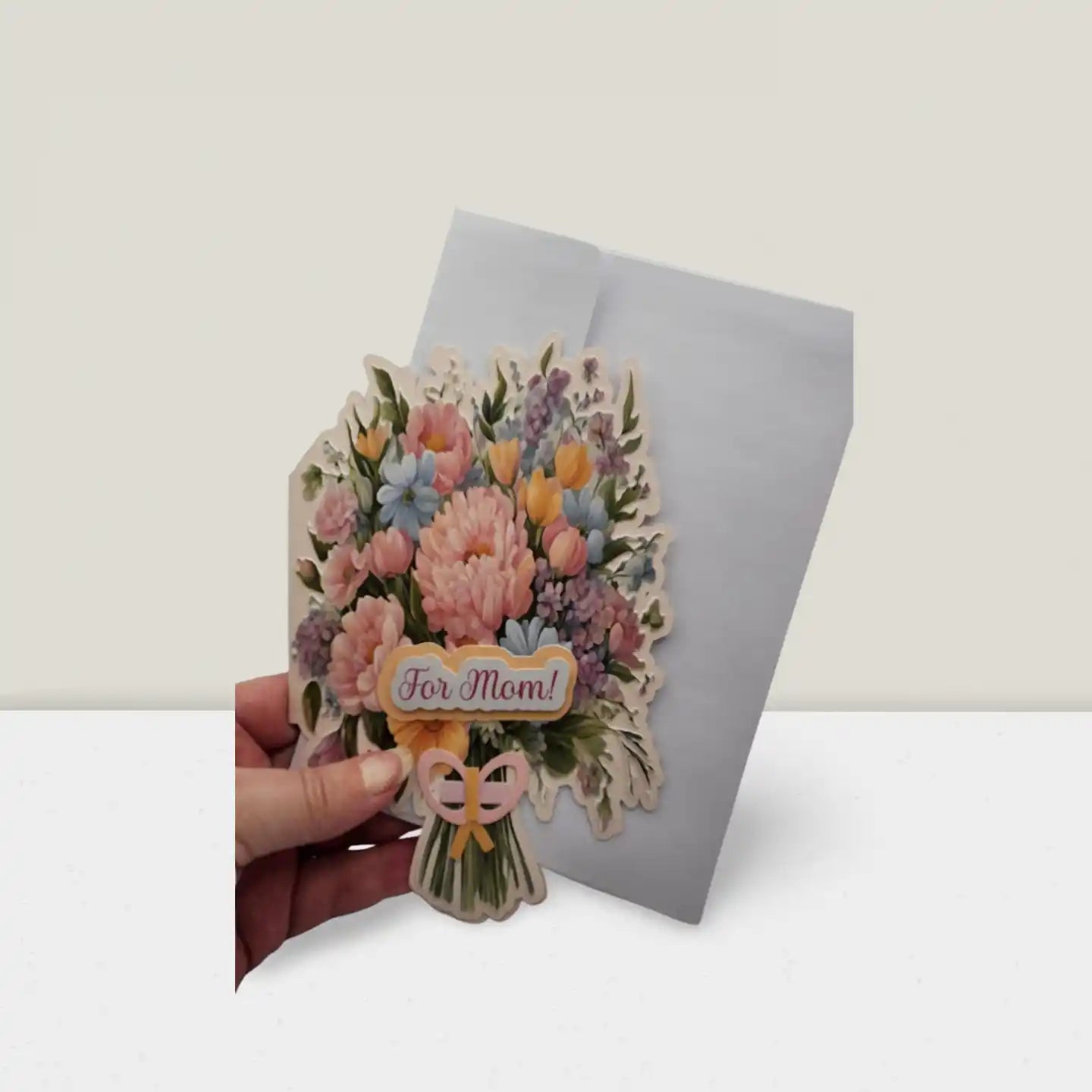 Floral card with 'For Mom' text held by a hand on a white background