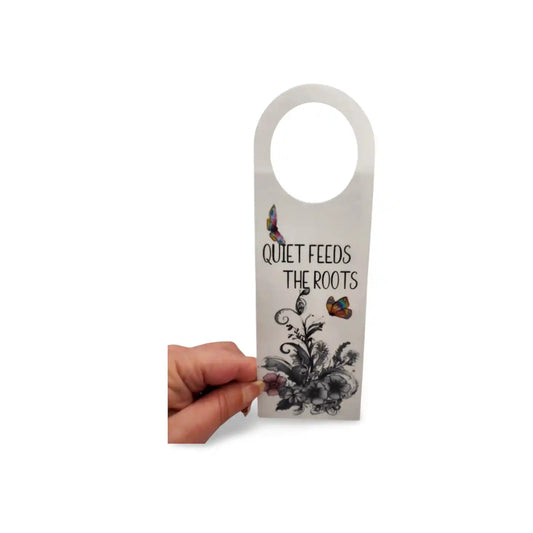 Hand holding a door hanger with floral design and text on a white background
