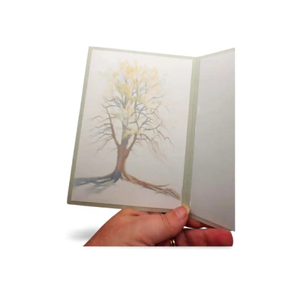 Hand holding a card with a tree illustration on a white background