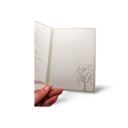Hand holding a card with a tree design on a white background