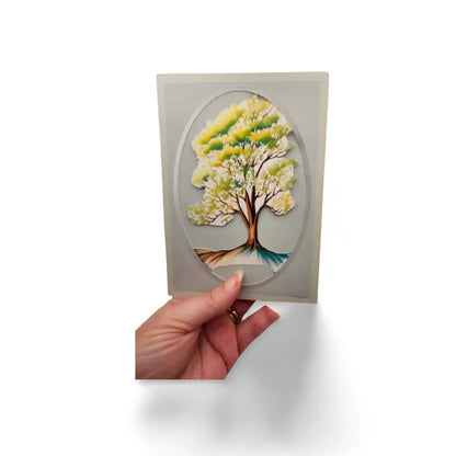 Hand holding a card with a tree design on a white background