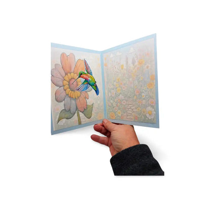 Hand holding a colorful pop-up card with a flower and bird design on a white background