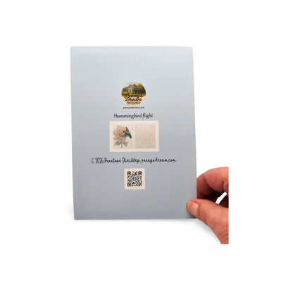 Hand holding a light blue card with a QR code and text on a white background