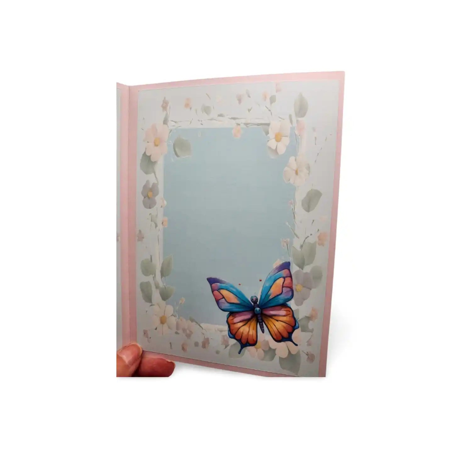 Greeting card with a colorful butterfly design on a light blue background, held by a hand.