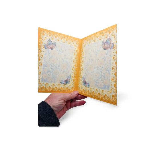 Hand holding a decorative card with butterfly designs on a white background
