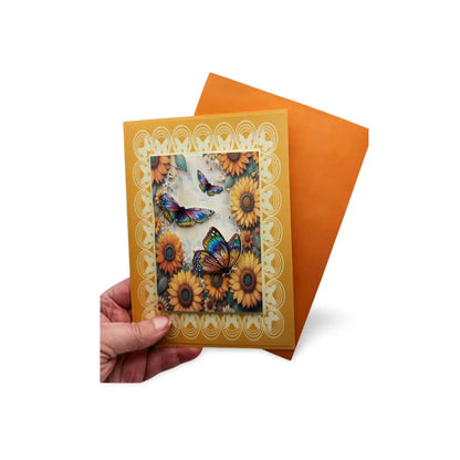 Hand holding a card with sunflowers and butterflies design on an orange envelope.