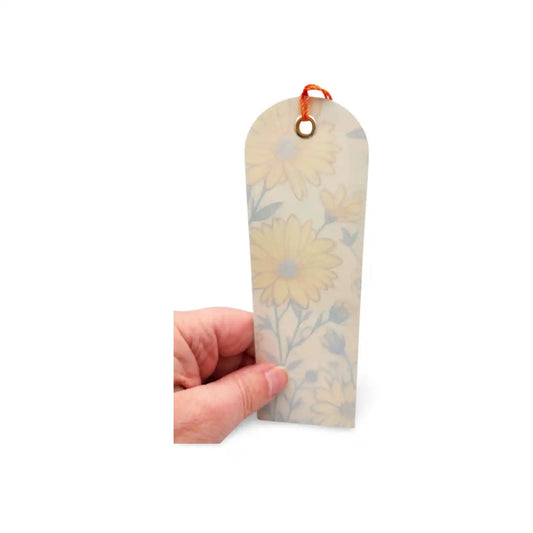 Floral bookmark held by a hand on a white background