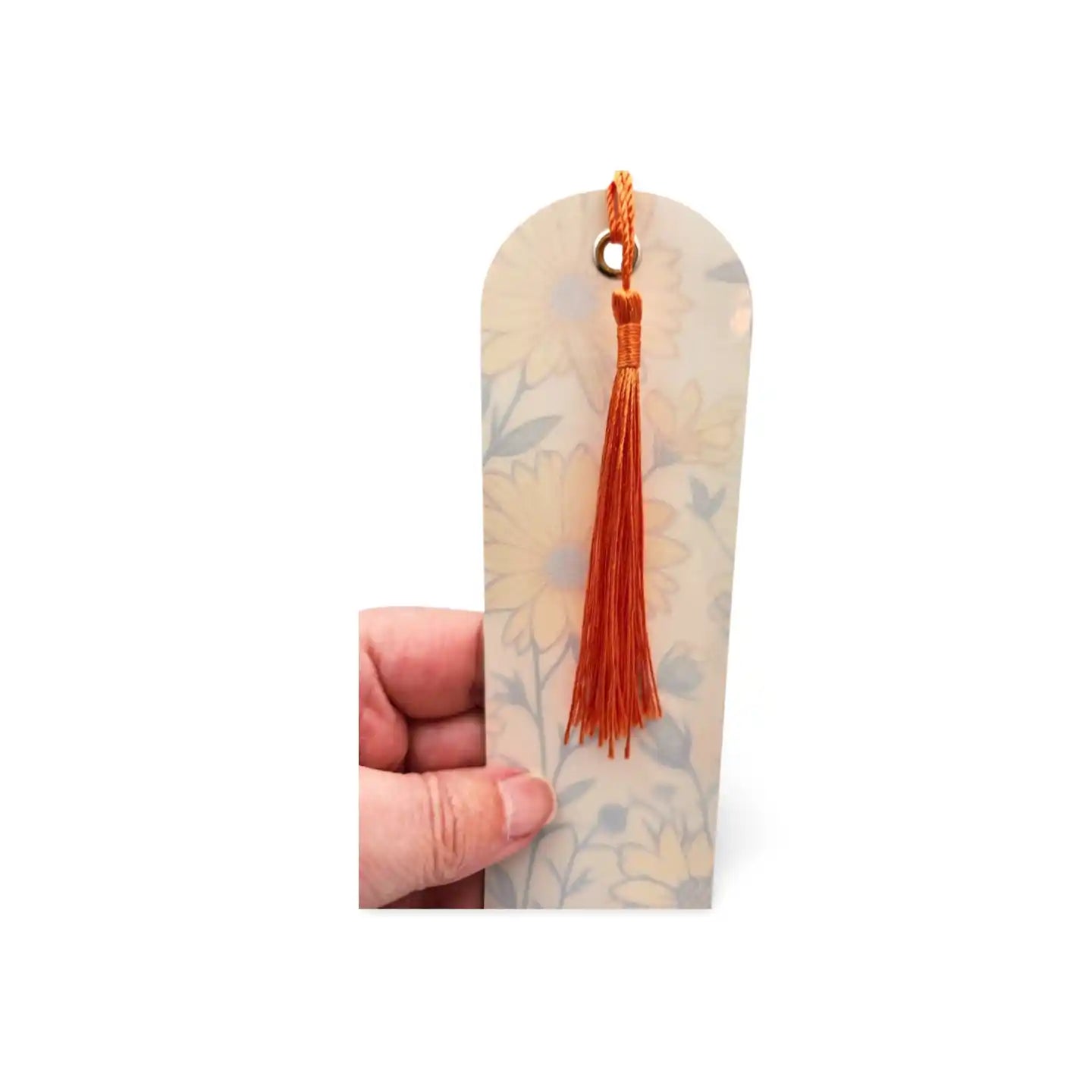 Decorative bookmark with a tassel held by a hand on a white background