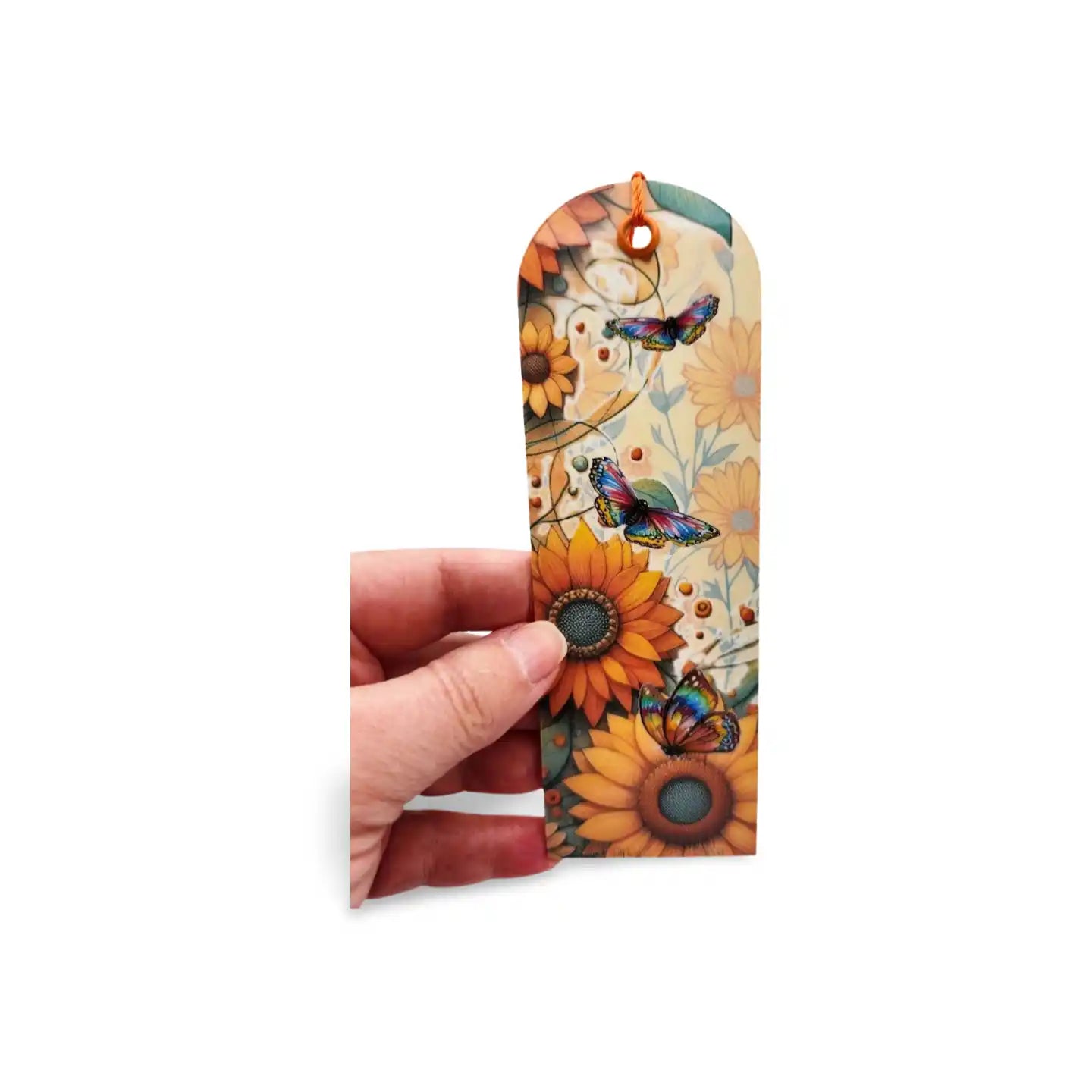 Hand holding a decorative bookmark with sunflowers and butterflies on a white background