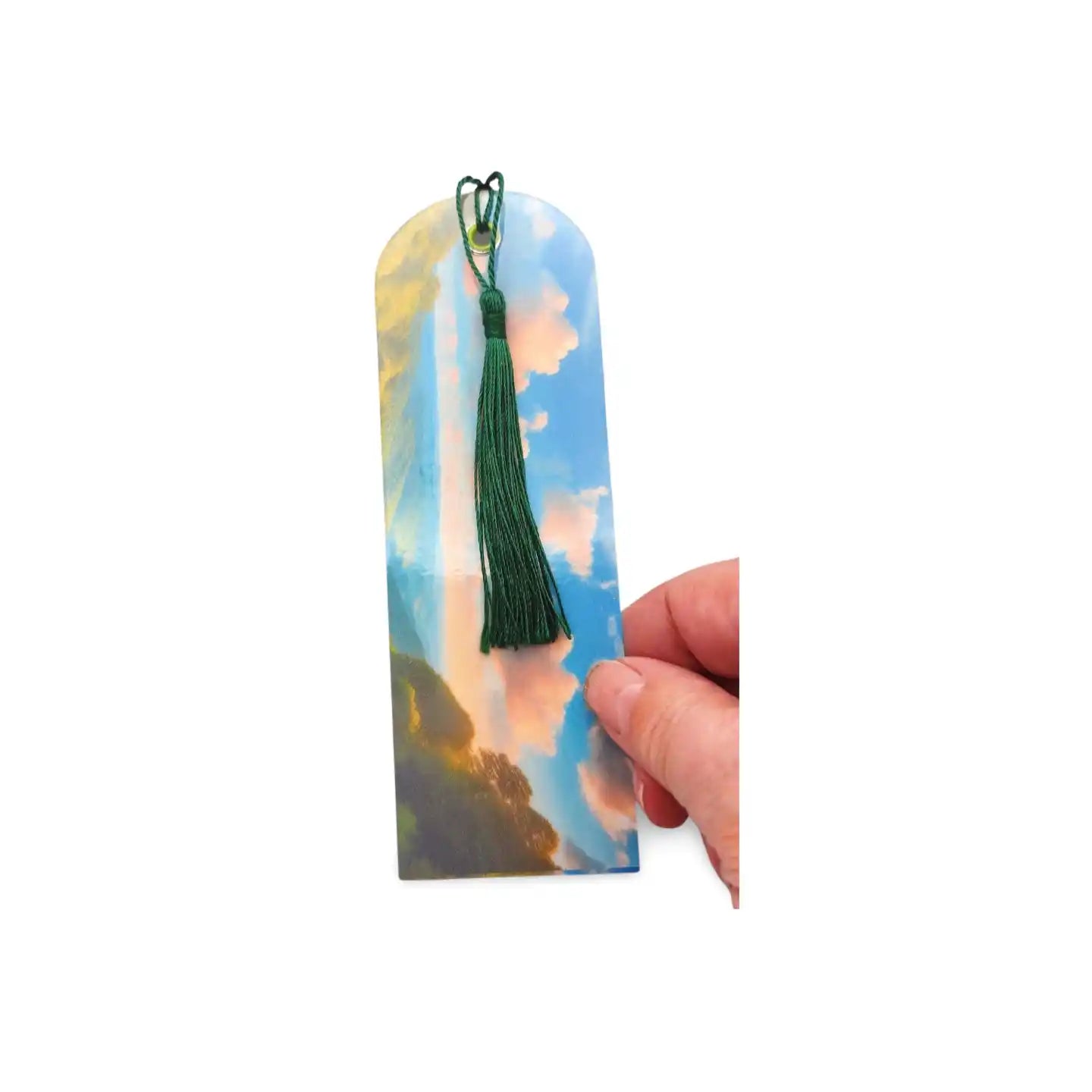 Hand holding a bookmark with a scenic design on a white background