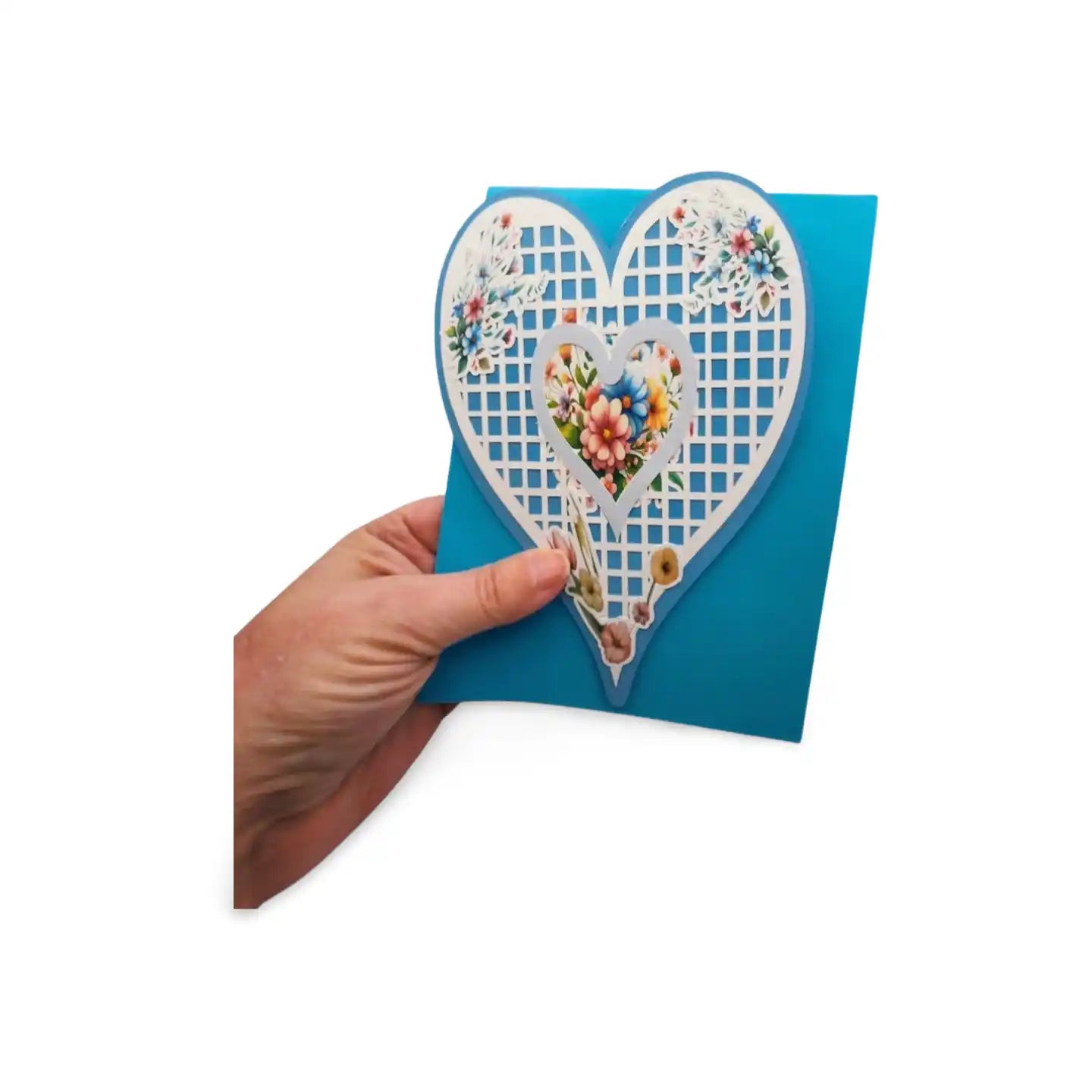 Hand holding a blue card with a decorative heart design on a white background